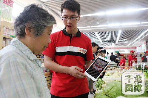 新改造后的西绒线菜市场，实行“实体+在线”的双模式。图为西长安街街道百姓生活服务中心工作人员教居民如何使用网上预约送菜服务 西长安街街道供图